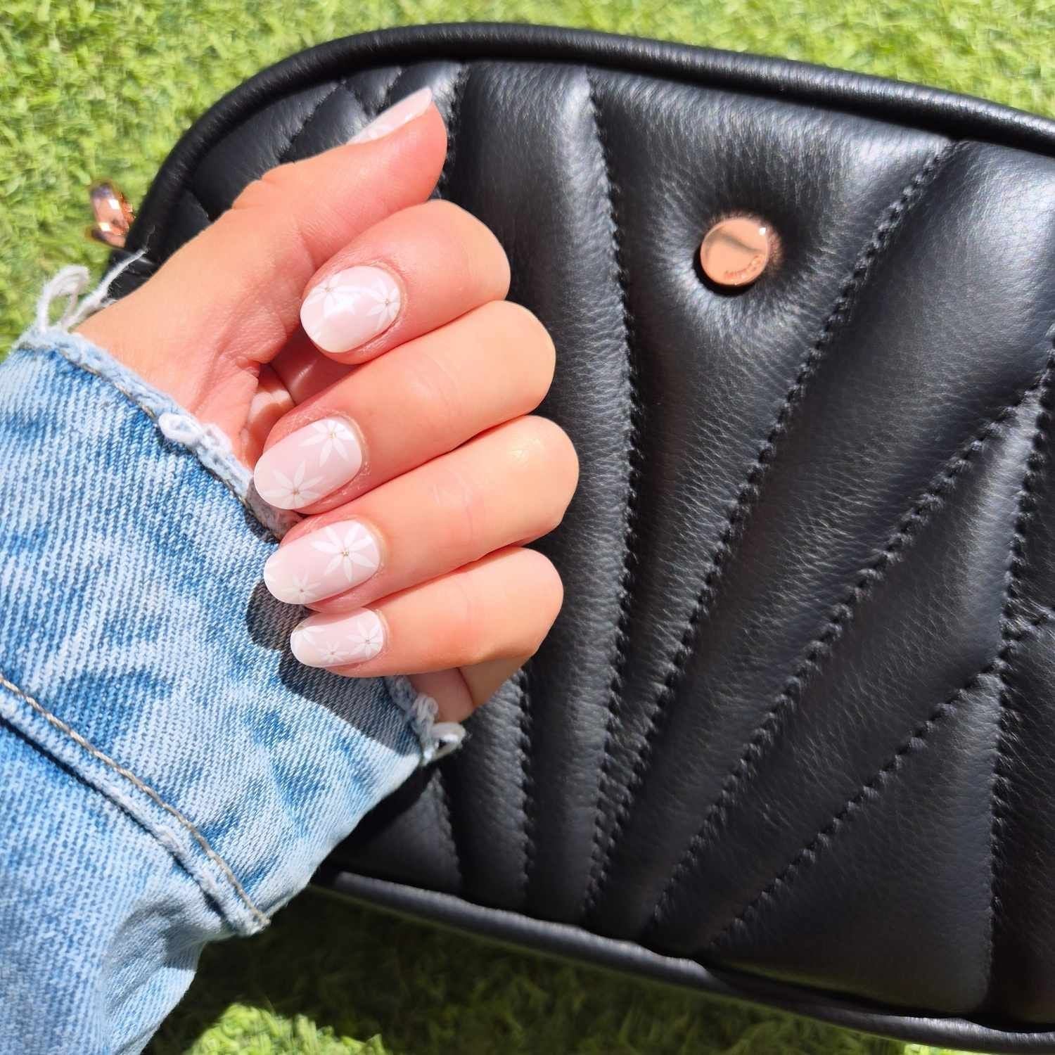 Hand holding a black quilted handbag with grass in the background